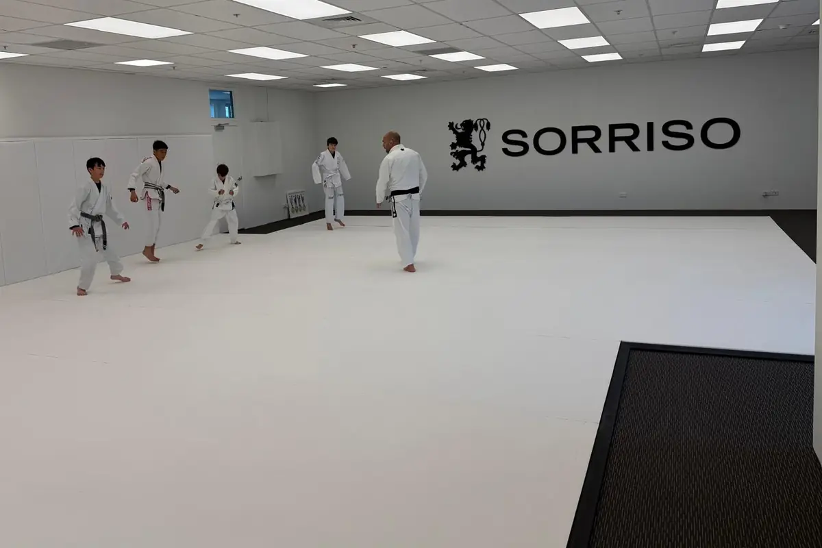 Kids warming up with their coach on the white mats at Sorriso BJJ Botany